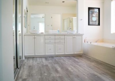 White cabinets and new flooring installed in the bathroom of a Squared Construction client.