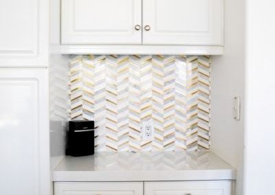 A kitchen desk and unique herringbone patterned backsplash using earth tones that Squared Construction added to a client's kitchen during a remodel.