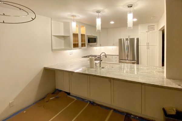 A remodeled kitchen where new countertops and custom white cabinets have been added.