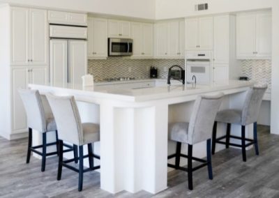A white marble island with seating space in a client's kitchen following a kitchen remodel in La Quinta.