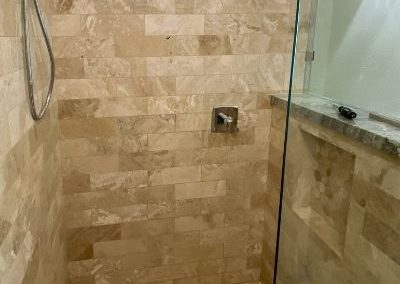 A small shower that has been updated and remodeled to add earth toned tiles