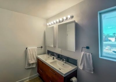 A simple bathroom remodel completed by Squared Construction featuring new cabinets, mirrors, and lighting.