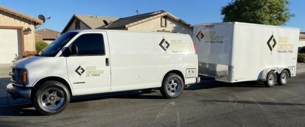A white work van and trailer bearing the logo of Squared Construction.