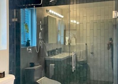 A newly remodeling shower featuring black subway tile installed in a unique pattern